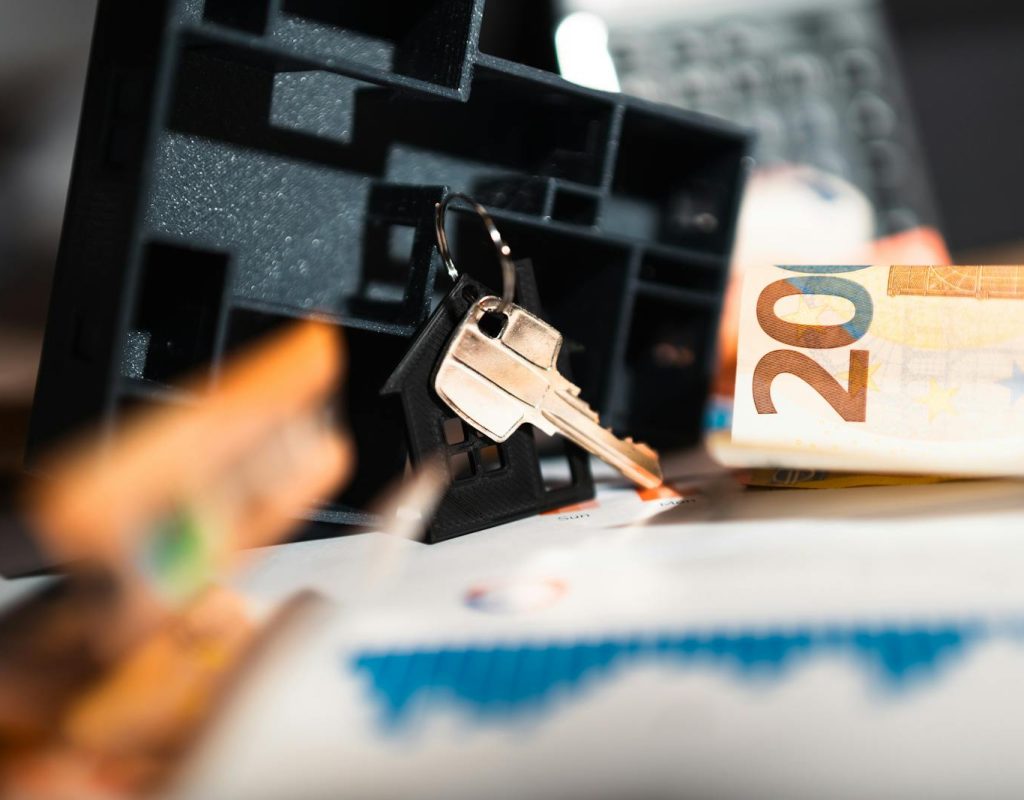 Keys with a house model, Euro bills, and charts suggesting real estate and financial themes.
