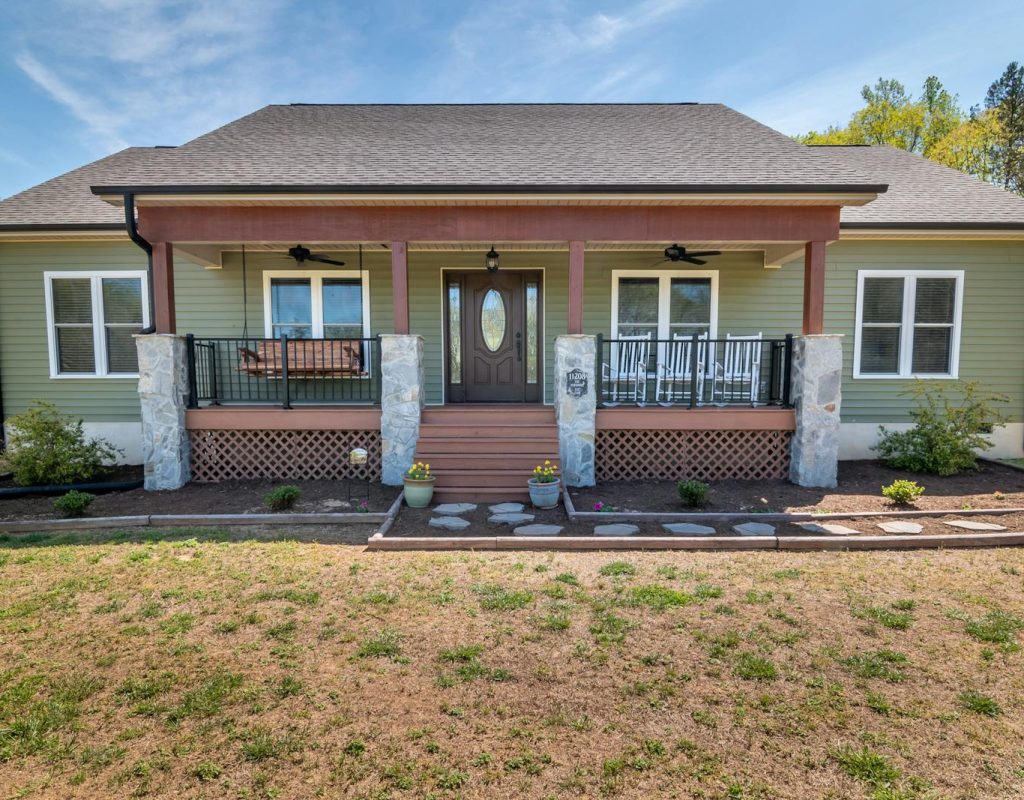 A cozy modern suburban family home with a spacious porch and landscaped yard.