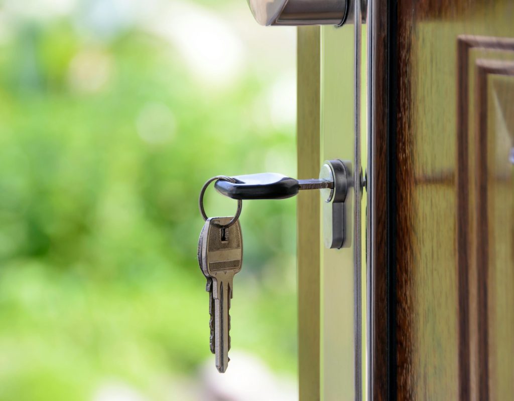 Key inserted in door lock against a blurred green background, symbolizing security and real estate.
