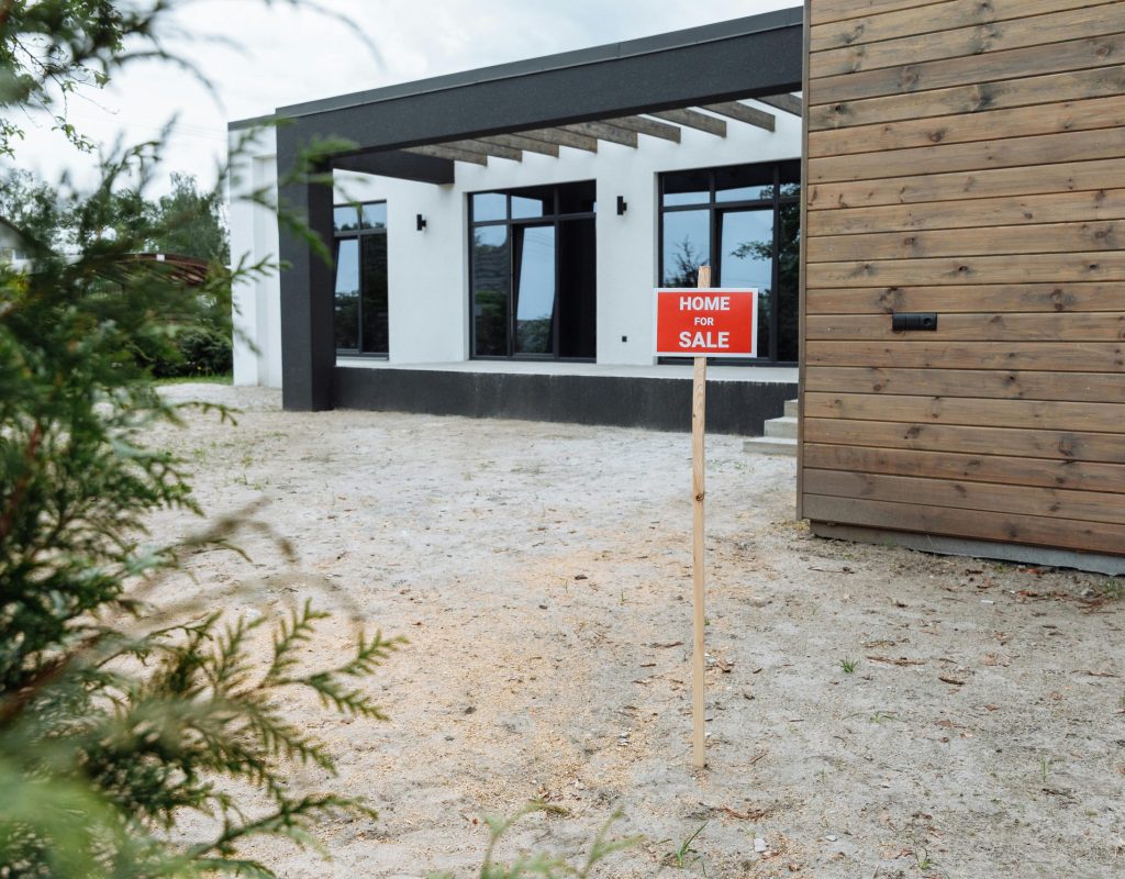 Modern house exterior with a 'Home for Sale' sign in front yard.